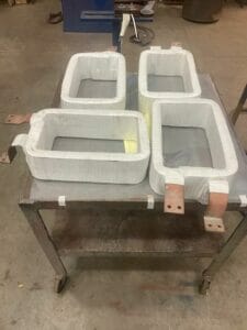 Four rectangular shaped reinsuled DC coils on a rolling machine shop cart