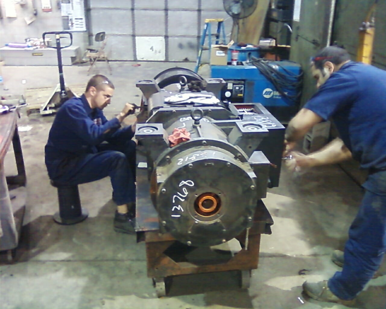 two technicians repairing a motor alternator unit